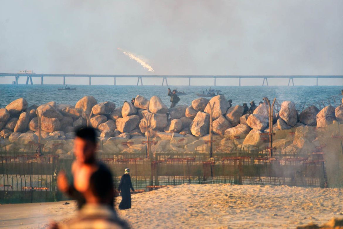 An Israeli soldier shoots tear gas cannisters at Palestinian demonstrators approaching the separation barrier between Gaza and Israel at the seaside on the Northern part of the Gaza Strip, during a pr