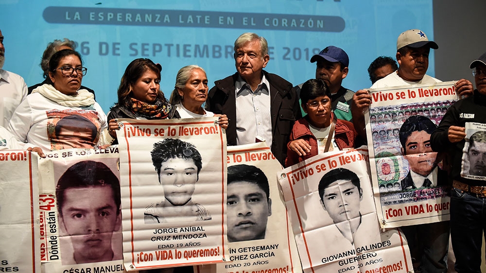 Mexican President-elect Andres Manuel Lopez Obrador poses with relatives of the 43 students of the teaching training school in Ayotzinapa who went missing in 2014 [Alfredo Estrella/AFP]
