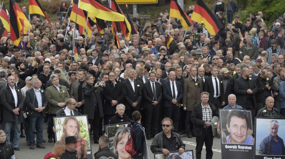 Demonstrators in Chemnitz hold photos of people they claim were killed by migrants after several nationalist groups called for marches protesting the killing of a German man, allegedly by refugees [Jens Meyer/AP]