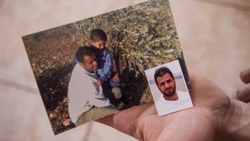 Ahmed holds photos of his father Mahmoud who was shot and killed by an Israeli settler last November [Tessa Fox/Al Jazeera]