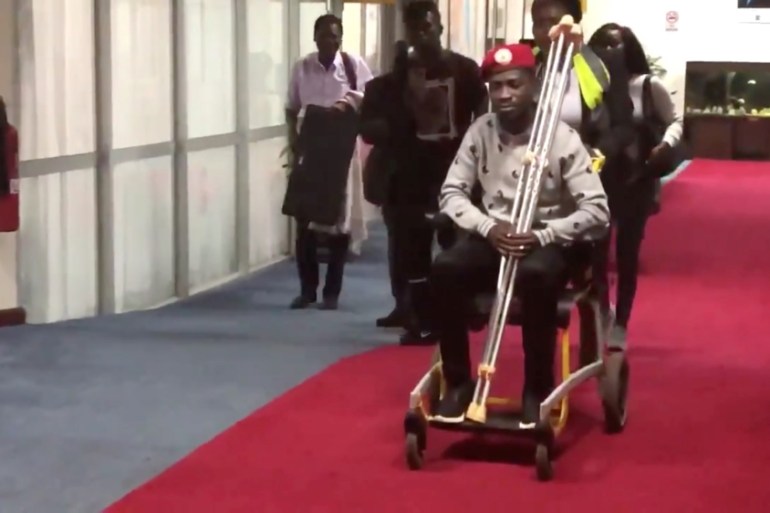 Bobi Wine is seen in a wheelchair just before his departure at Entebbe International Airport, in Entebbe