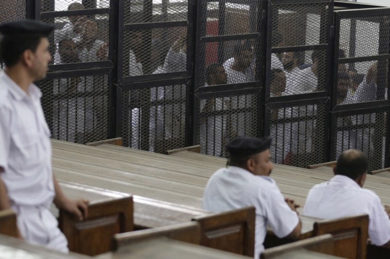 Islamist defendants stand behind bars in the case known as the "Kerdasa massacre'''' in Cairo