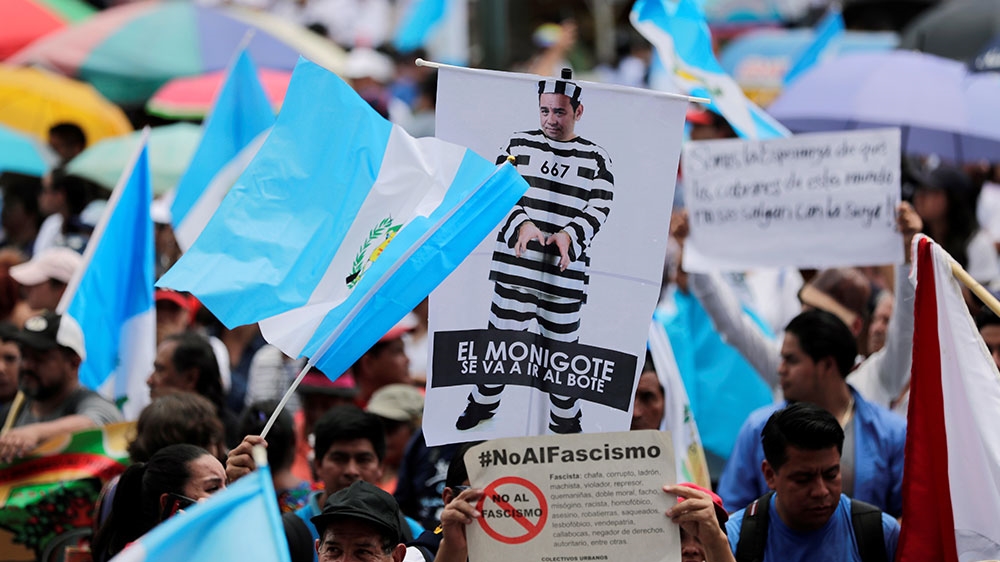 A demonstrator holds up a poster of Guatemala President Jimmy Morales as a prisoner, during a protest against Morales's decision to not renew the mandate CICIG [Luis Echeverria/Reuters] 