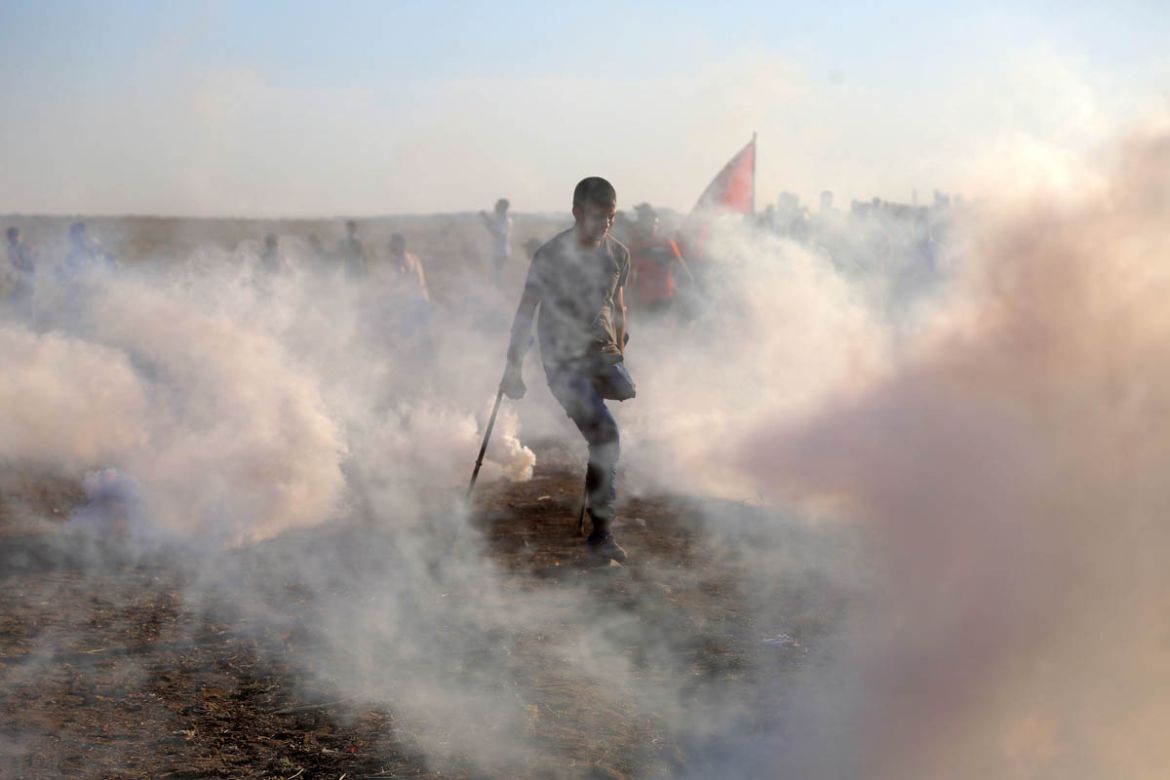 A Palestinian with a missing limb runs from tear gas during a protest at the Gaza fence, east of Gaza city, August 10, 2018. Bullets used by Israeli forces against protesters have caused extreme destr