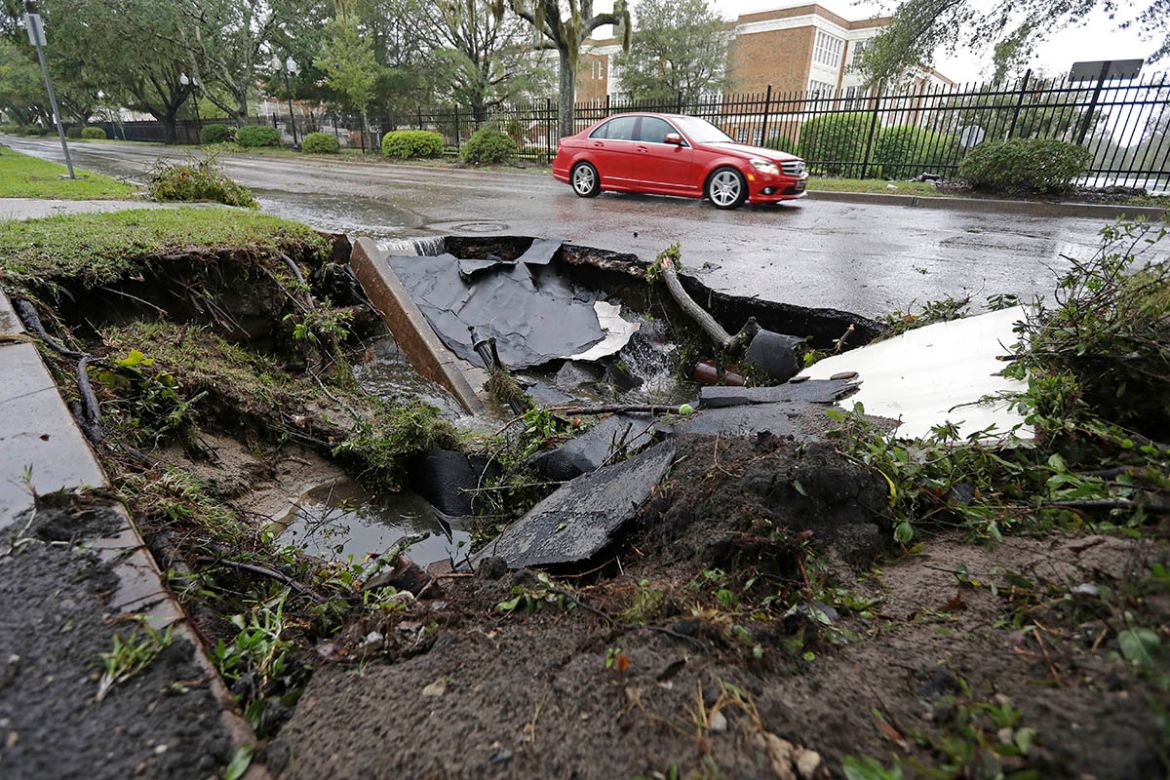 A car travels past a sinkhole in downtown Wilmington, N.C., after Hurricane Florence traveled through the area Sunday, Sept. 16, 2018. (AP Photo/Chuck Burton)