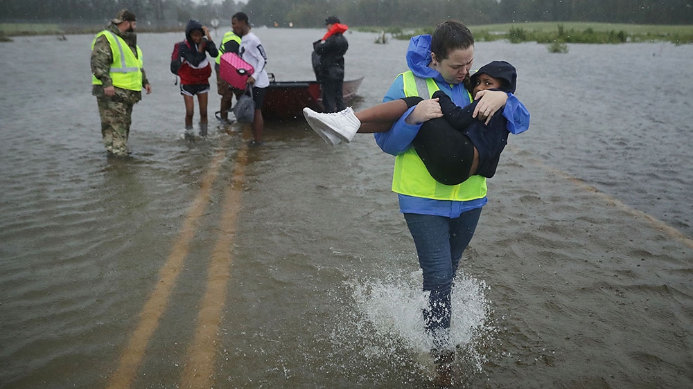 Volunteers help rescue three children from their flooded home in James City, North Carolina [Chip Somodevilla/Getty Images/AFP]