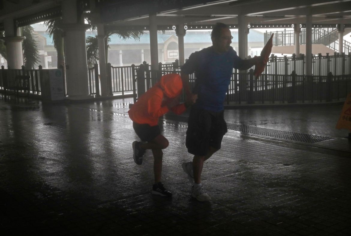 A man and a girl walk against strong winds from Typhoon Mangkhut on a pier on Victoria Habour Hong Kong, Sunday, Sept. 16, 2018. Hong Kong and southern China hunkered down as strong winds and heavy ra