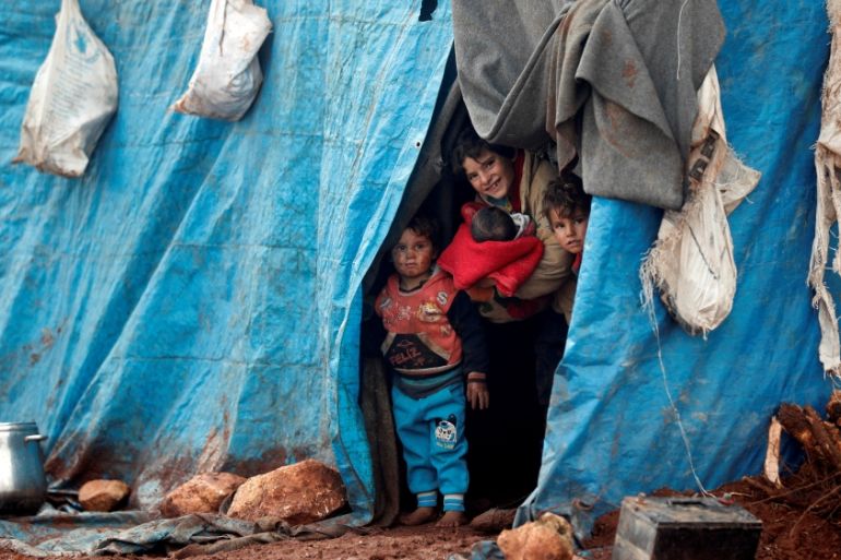 Displaced Syrian children look out from their tents at Kelbit refugee camp in Idlib province