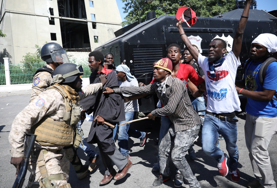 Haitian National Police officers stop protesters near the National Palace during a march to demand an investigation into what they say is the alleged misuse of Venezuela-sponsored PetroCaribe funds, i