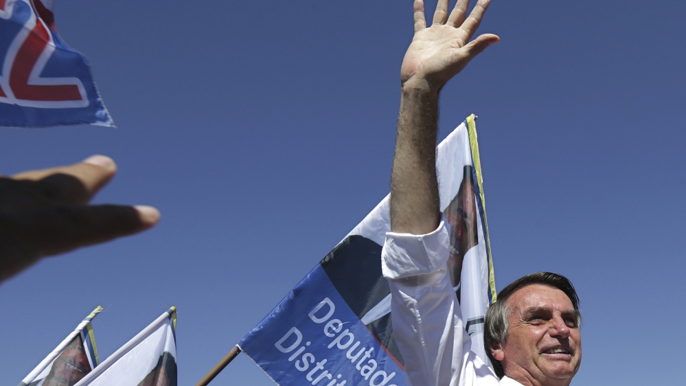 Jair Bolsonaro greets supporters during a campaign rally in Brasilia [File: Eraldo Peres/AP Photo]