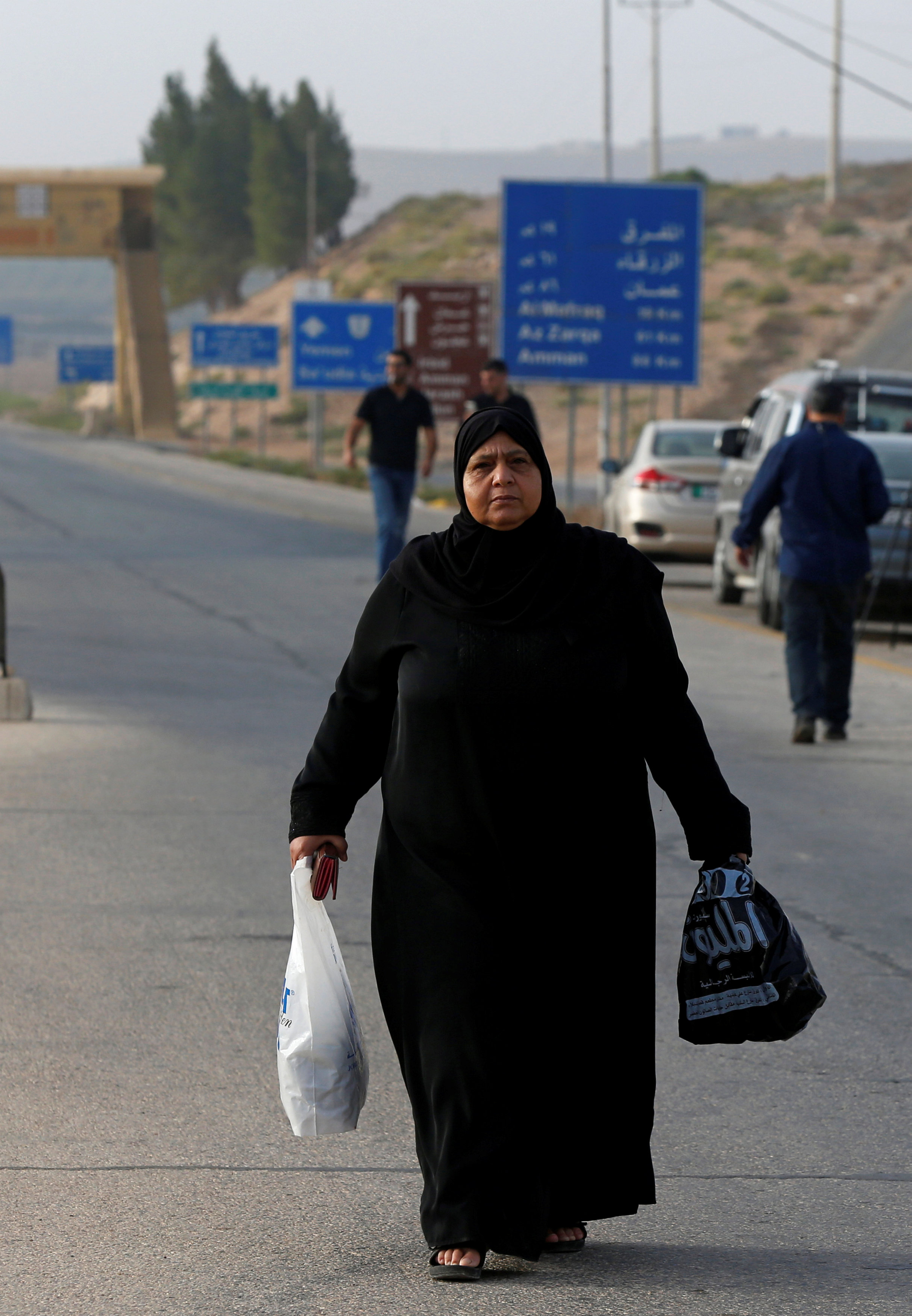 A Syrian woman walks towards the crossing checkpoint border between Jordan and Syria [Muhammad Hamed/Reuters] 