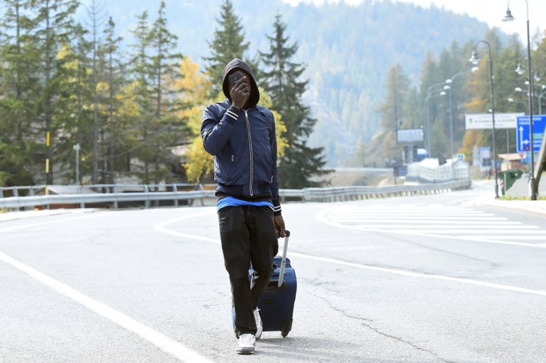 A migrant walks along the road next to the French border in Claviere