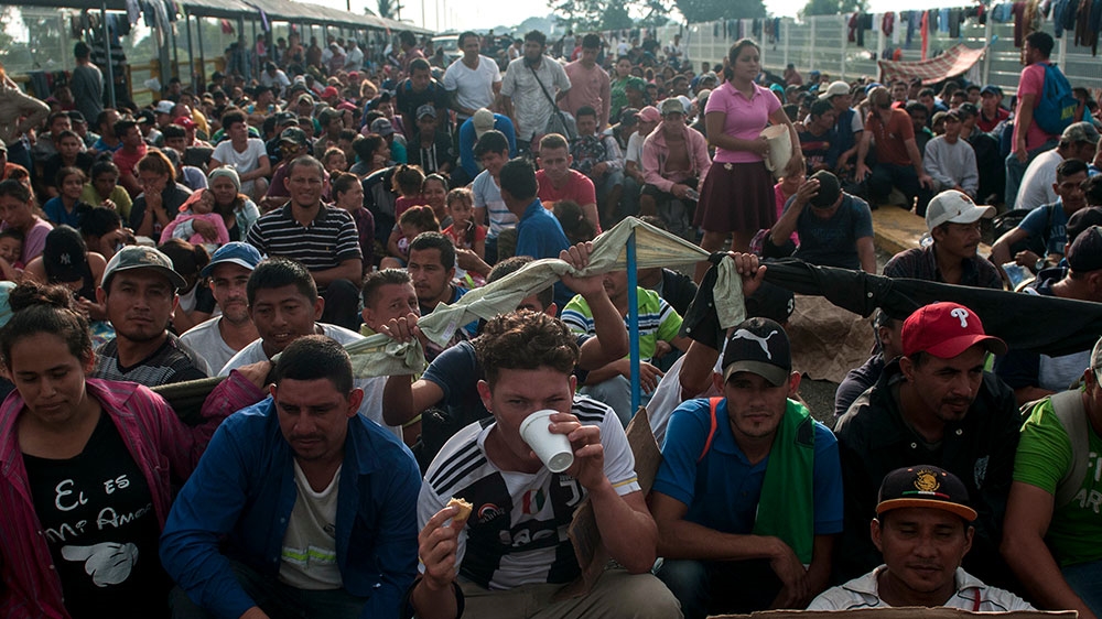 Honduran migrants wait to be attended to by Mexican migration authorities on a bridge that stretches over the Suchiate River, connecting Guatemala and Mexico, in Tecun Uman, Guatemala [Oliver de Ros/AP Photo] 