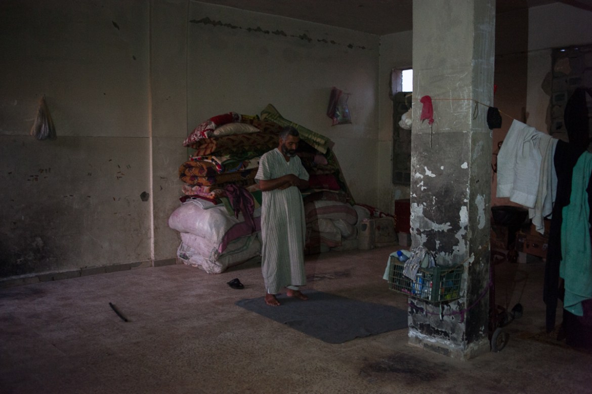 A man prays on the ground floor of the abandoned school of Harijieh, 80 km North from Hajin. Hundred people from Deir ez-Zor found home in the empty rooms of the building. September 2018