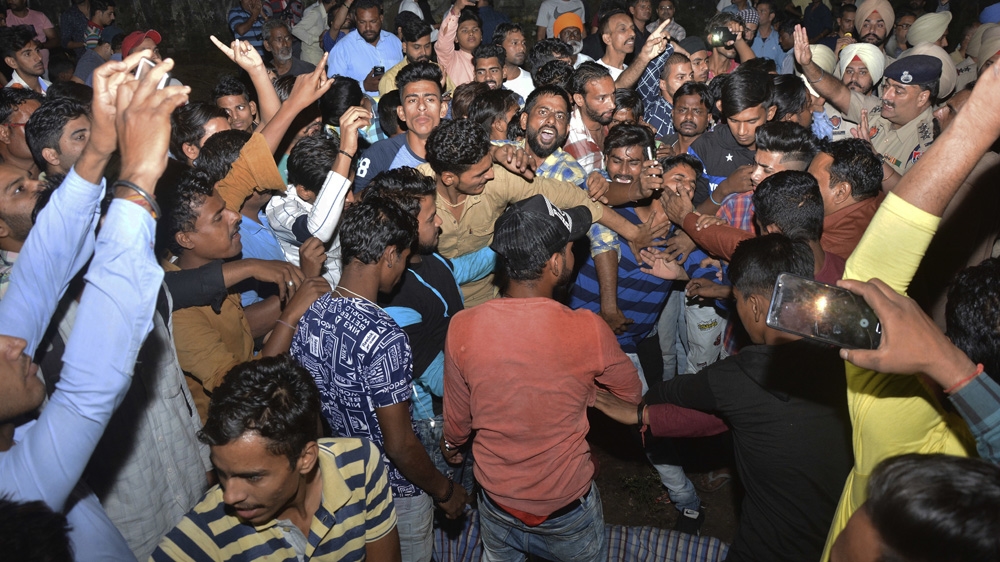 A crowd shouts slogans beside the body of a victim of the train accident [AP Photo/Prabhjot Gill]