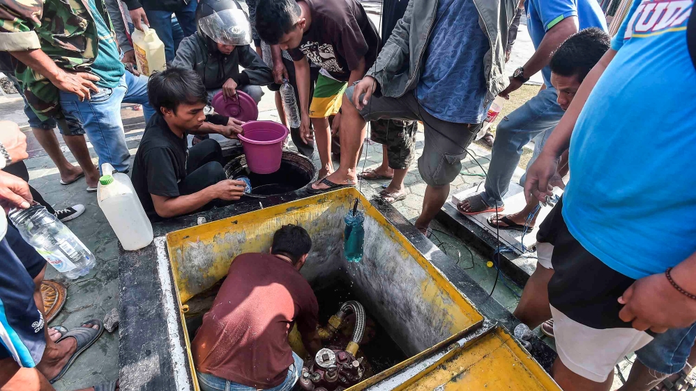 People collect fuel from a storage tank at a petrol station in Palu, Central Sulawesi [Antara Foto/ Muhammad Adimaja/via Reuters]