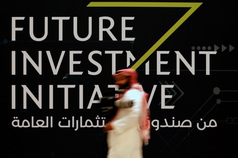 A man walks past a sign at the Future Investment Initiative conference in Riyadh