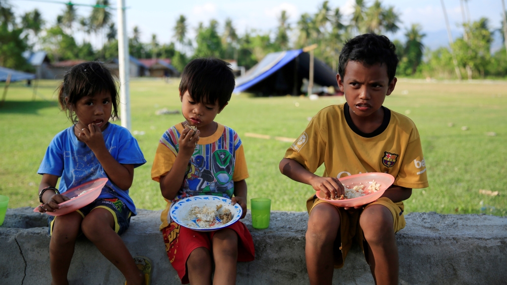 Children eat outside their tent for safety reasons after the earthquake in Biromaru village in Sigi [Beawiharta/Reuters]