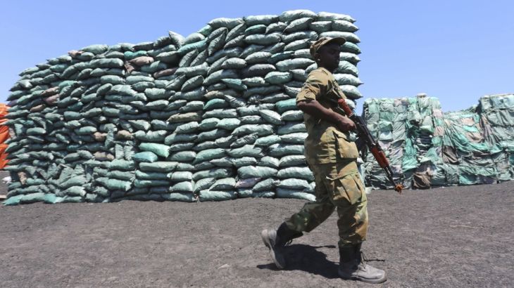 A Somalian soldier walks past a consignment of charcoal destined for the export market in Barawe