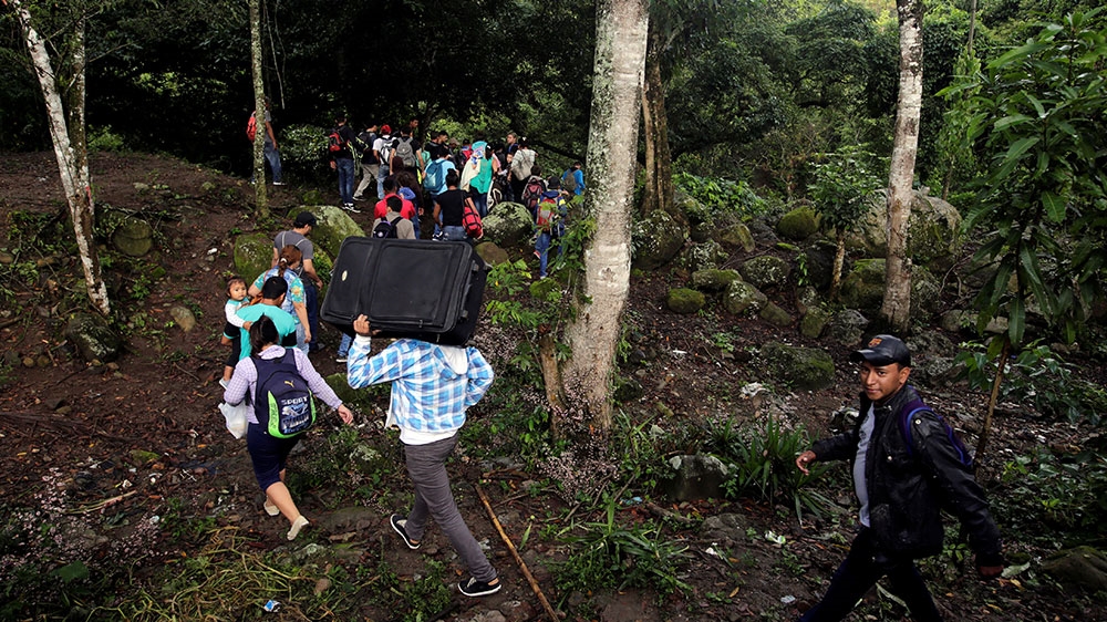 Honduran migrants hike through the forest after crossing the Lempa river, on the border between Honduras and Guatemala, to join a caravan trying to reach the US [Jorge Cabrera/Reuters]