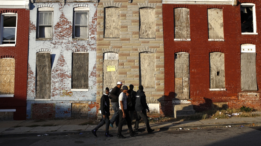 Young men walk past abandoned houses in the Sandtown-Winchester neighbourhood of Baltimore, a block away from where Freddie Gray was arrested [AP Photo/Patrick Semansky]