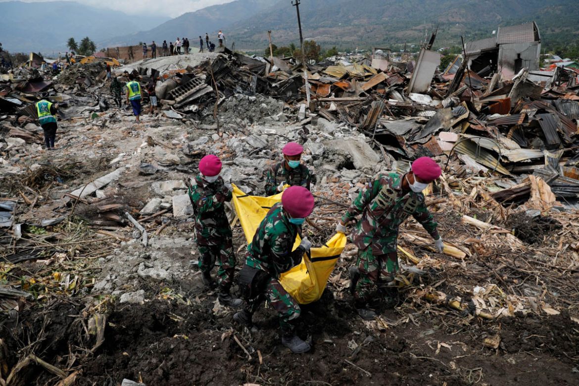 Indonesian soldiers carry a dead body from the ruins of houses after an earthquake hit Balaroa sub-district in Palu, Indonesia, October 4, 2018. REUTERS/Beawiharta