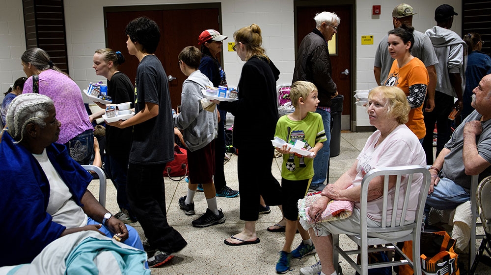 People wait for breakfast as they and others seek safety in a shelter as Hurricane Michael approaches Panama City, Florida [Brendan Smialowski/AFP]