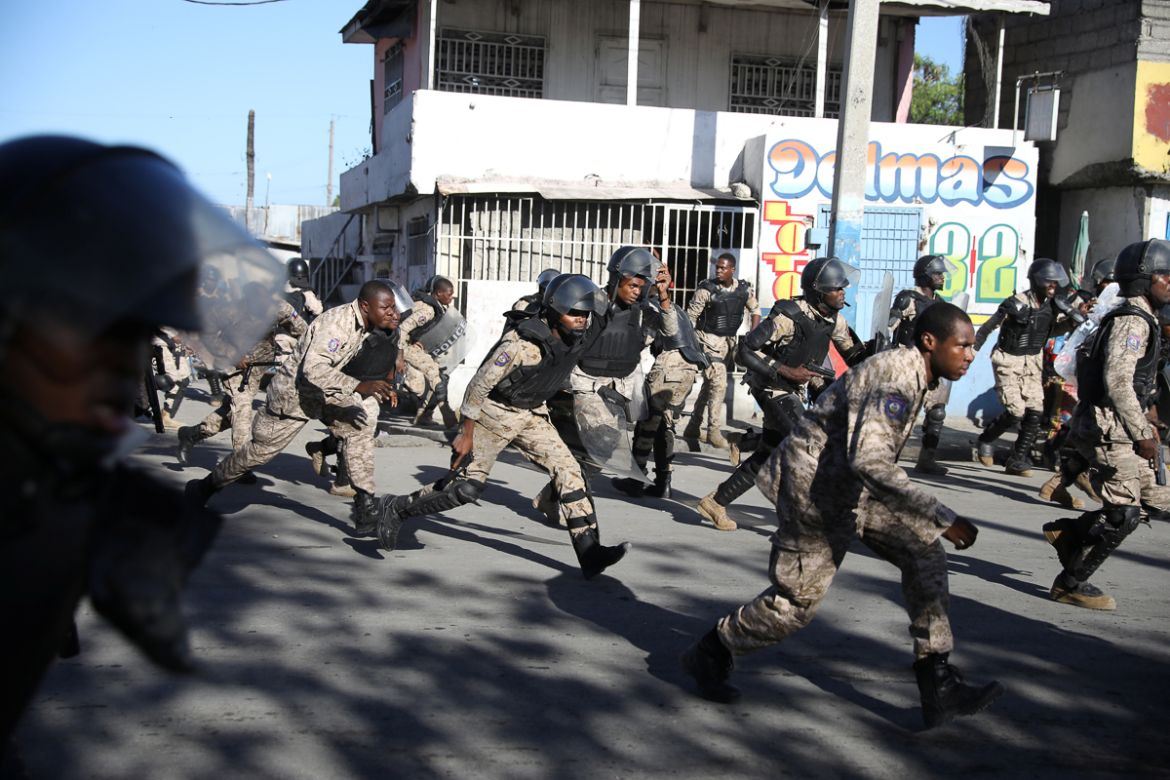 Haitian National Police officers take cover during a shooting after a ceremony for the anniversary of the killing of Jean-Jacques Dessalines in Port-au-Prince, Haiti October 17, 2018. Civil society ha