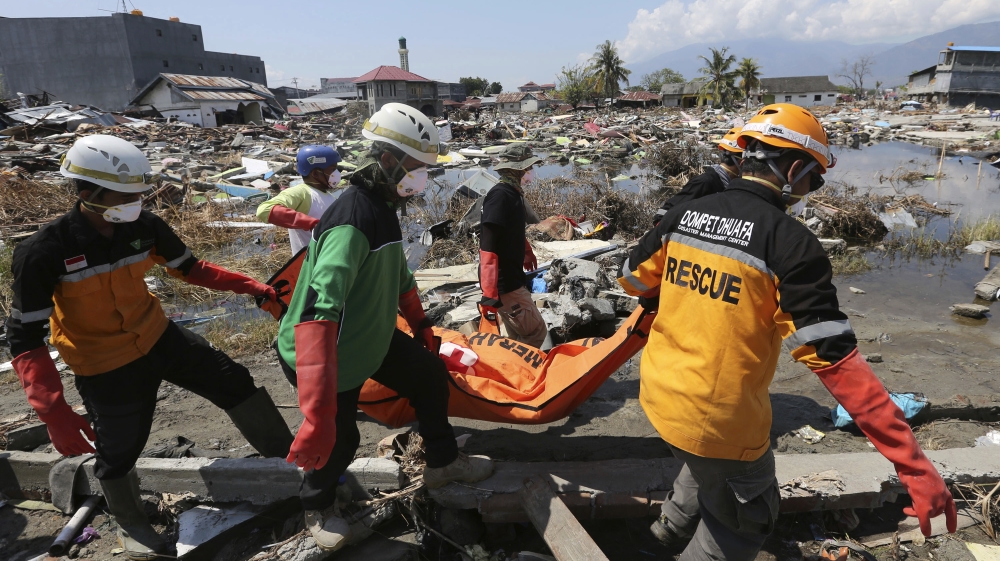 An Indonesian rescue team carries the body of a victim following an earthquake and tsunami in Palu [Tatan Syuflana/AP Photo]