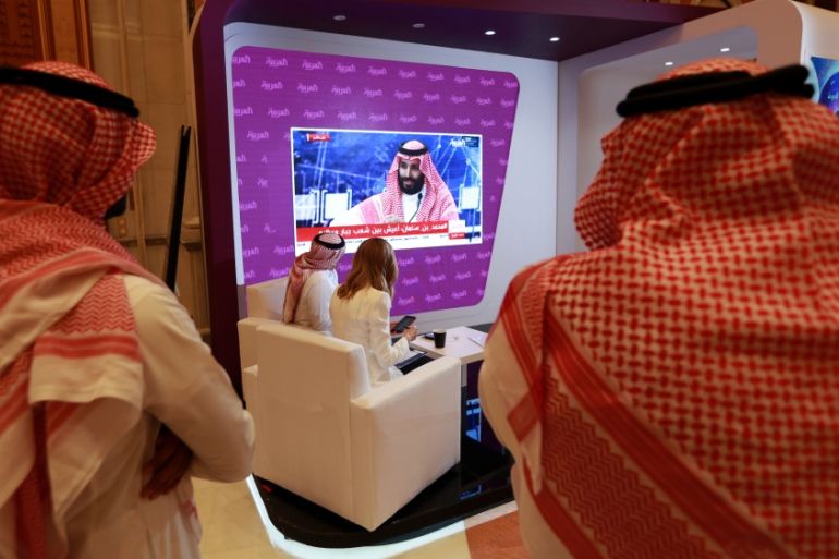 Participants watch on TV, as Saudi Crown Prince Mohammed bin Salman as he delivers a speech during the Future Investment Initiative Forum in Riyadh