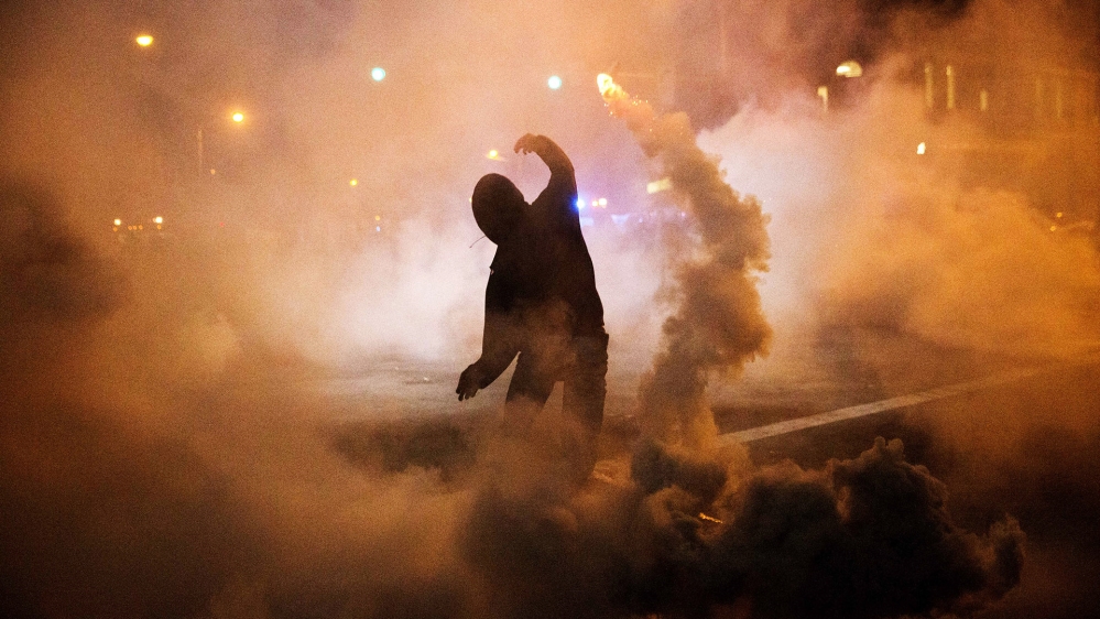 A protester throws a tear gas canister back towards riot police after a 10pm curfew went into effect following the funeral for Freddie Gray on April 28, 2015, in Baltimore [AP Photo/David Goldman]