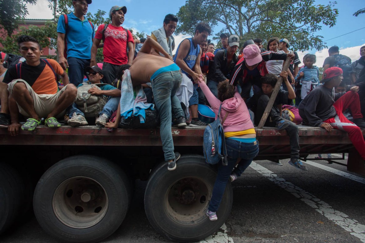 Migrants climb on a truck that stopped to provide a ride to Chiquimula, but the group eventually declined the ride in order to stay together and improve security for the group on October 21.