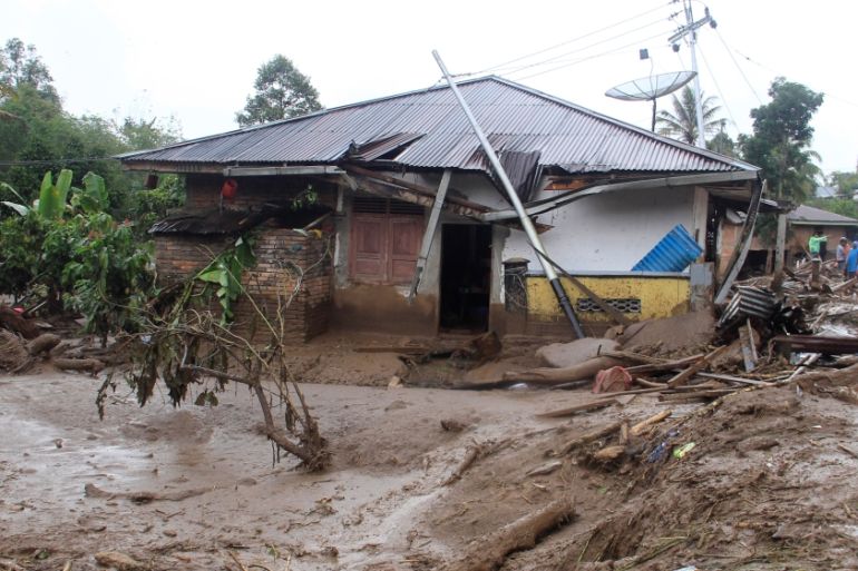 Villagers stand near a damaged house after floods hit Nagari Tanjung Bonai village in Tanah Datar