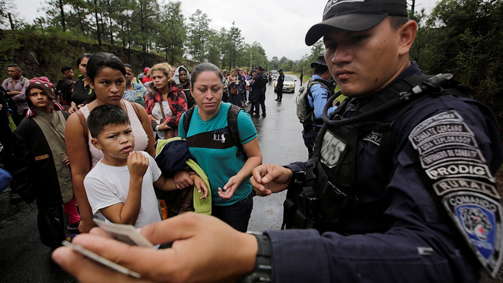 Honduran migrants show their identification to an official near to the Agua Caliente border, hoping to cross into Guatemala and join a caravan trying to reach the US [Jorge Cabrera/Reuters] 