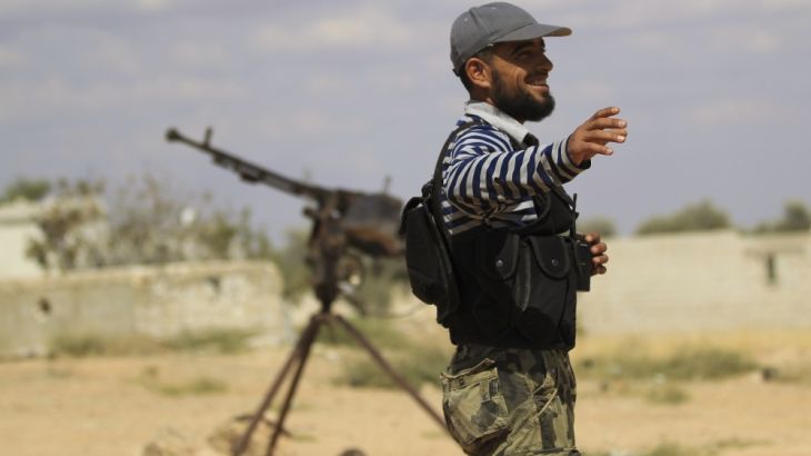 A Free Syrian Army fighter gestures beside a machine gun on one of the front lines of Wadi Al-Daif camp in the southern Idlib countryside