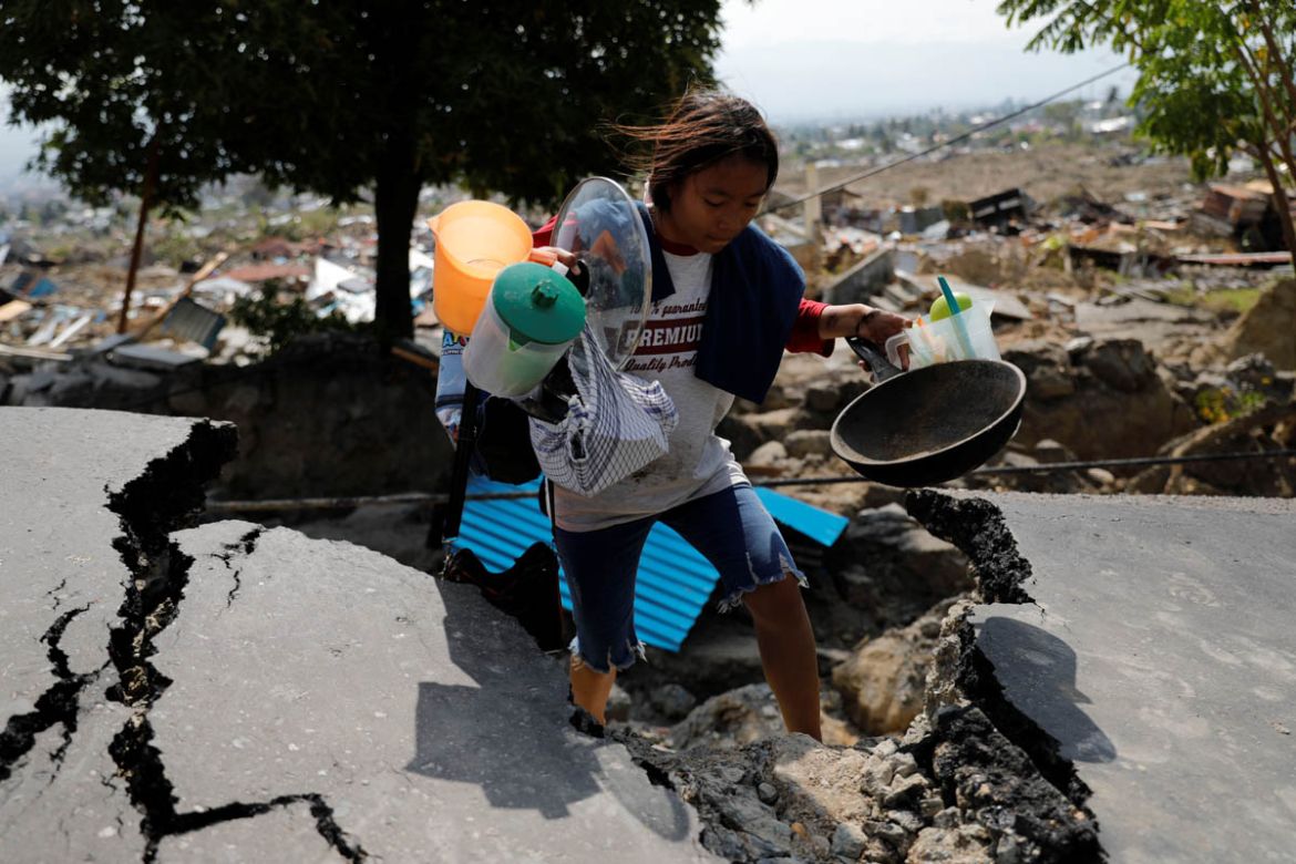 A girl carries valuables from the ruins of her house after an earthquake hit the Balaroa sub-district in Palu, Indonesia, October 4, 2018. REUTERS/Beawiharta