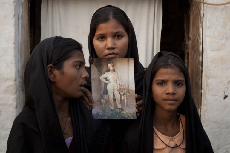 The daughters of Pakistani Christian woman Asia Bibi pose with an image of their mother while standing outside their residence in Sheikhupura located in Pakistan''s Punjab Province November 13, 2010.