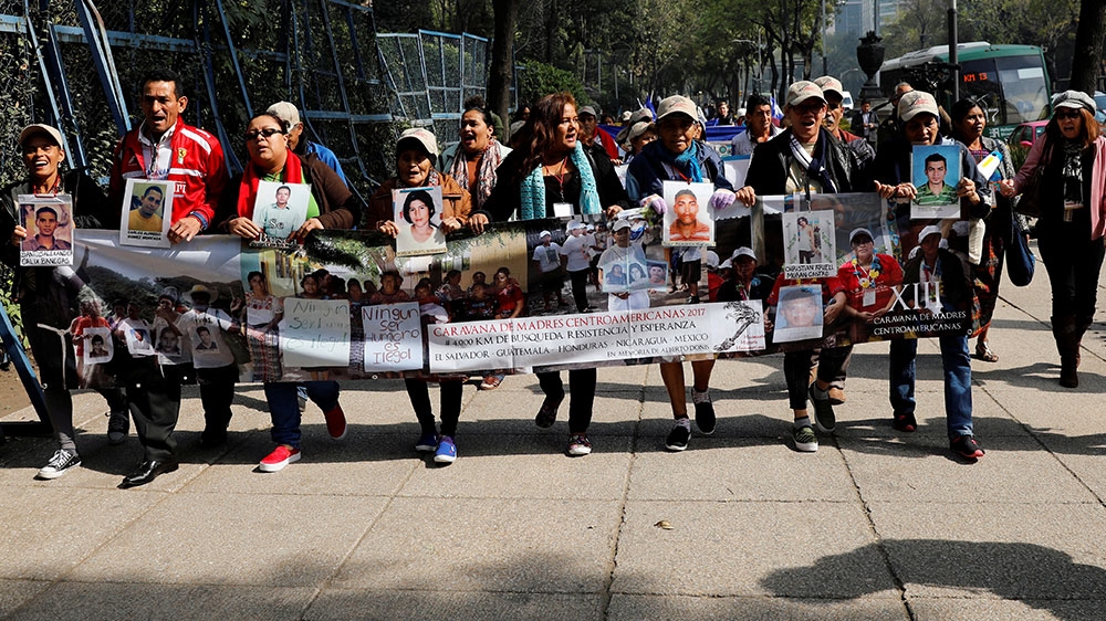 Women of the Caravan of Central American Mothers hold up photos of missing migrants as they protest against President Donald Trump's anti-immigrant policy in front of the US embassy in Mexico City [Carlos Jasso/Reuters] 