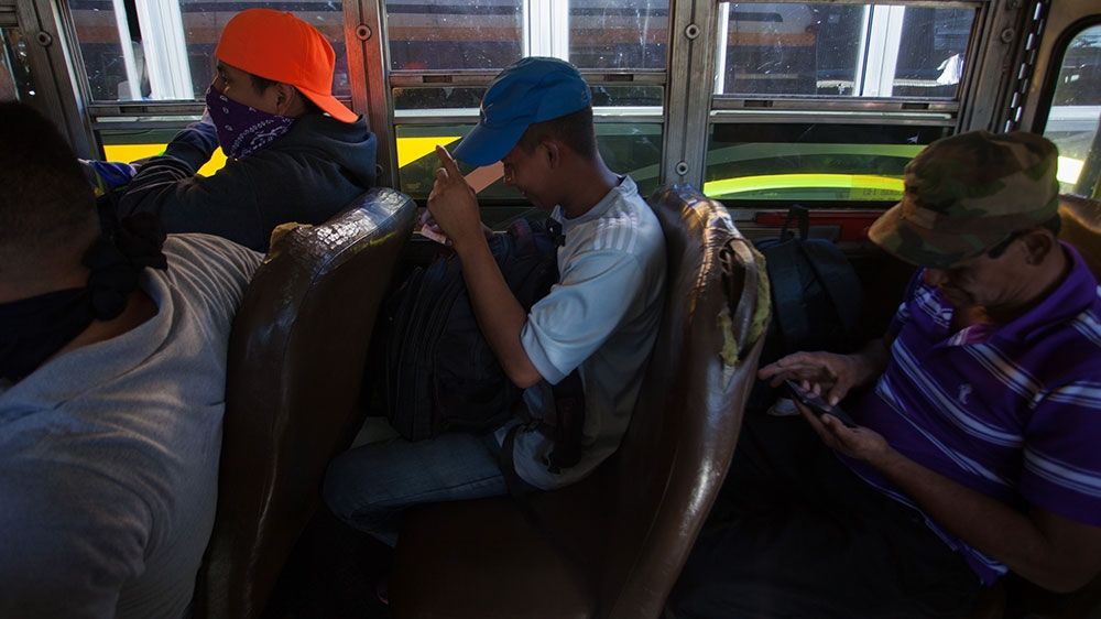 Salvadoran migrants wait in a bus to leave San Salvador for the country’s border with Guatemala [Jeff Abbott/Al Jazeera] 