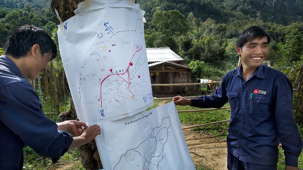A MAG community liaison team at work in Ban Nator, a small village of 26 families in Xiengkhouang Province. MAG personnel develop maps with the villagers to help locate UXO, including the sites of accidents and UXO- contaminated areas most needed by the community [Courtesy: MAG]