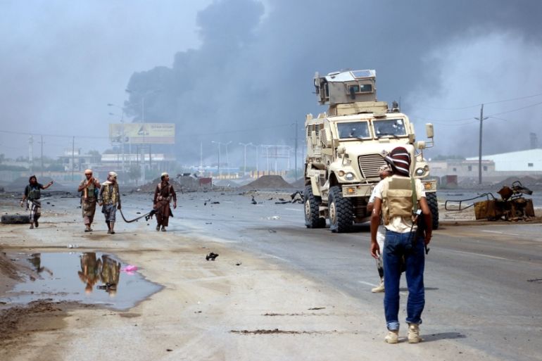 Yemeni government forces patrol as smoke billows from an alleged Houthi position during battles between Yemeni government forces and Houthi rebels in the port city of Hodeidah