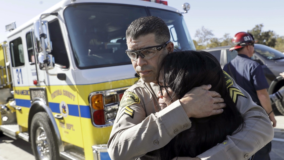 Los Angeles County Deputy Sheriff Armando Viera, centre, consoles an unidentified woman [Marcio Jose Sanchez/AP Photo]
