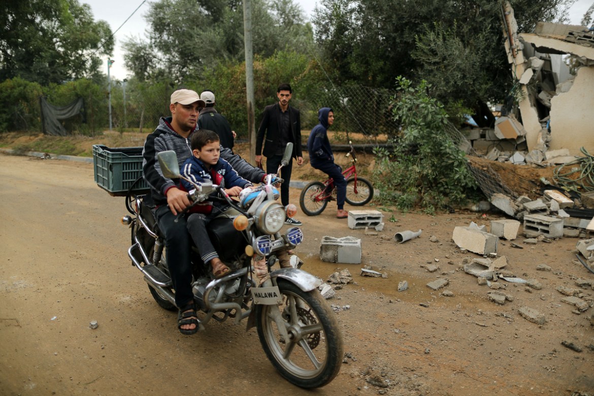 A Palestinian man and his son ride a motorcycle past the debris of a building destroyed in an Israeli air strike, in Khan Younis in the southern Gaza Strip November 12, 2018. REUTERS/Suhaib Salem