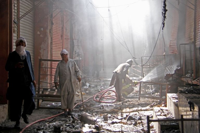FILE PHOTO: An Afghan firefighter sprays water on burning shops after a Taliban attack in Ghazni city,
