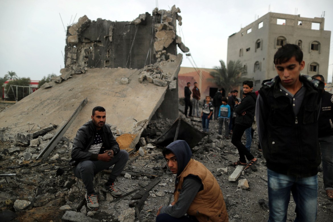 Palestinians sit at the remains of a building that was destroyed by an Israeli air strike, in Khan Younis in the southern Gaza Strip November 12, 2018. REUTERS/Suhaib Salem