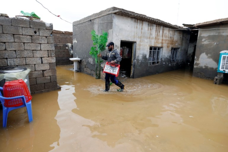 A man cleans his house after heavy rainfall in al-Aziziyah