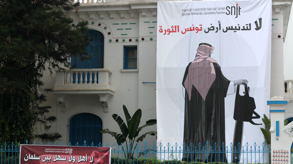 A banner depicts Prince Mohammed holding a chainsaw and reads 'no to the desecration of Tunisia, land of the revolution' [Asma Ajroudi/Al Jazeera]
