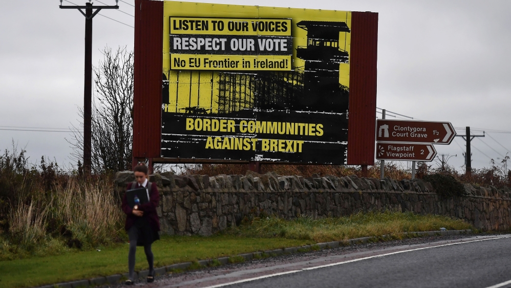 A student walks past a Border Communities Against Brexit sign in Newry, Northern Ireland [Charles McQuillan/Getty Images]