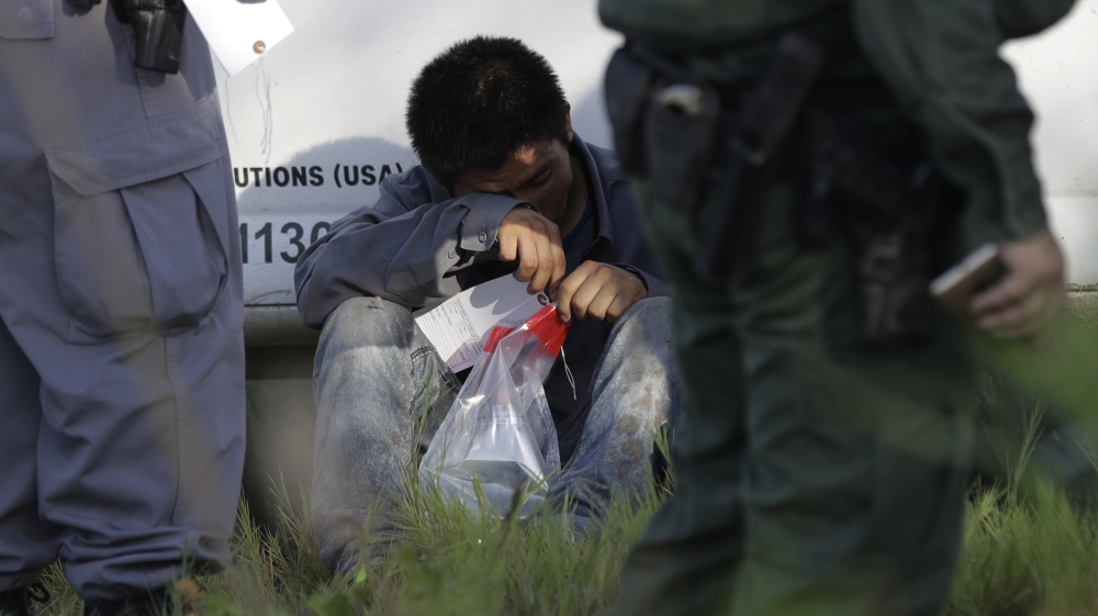 A man suspected of crossing into the United States between official ports of entry along the Rio Grande near Granjeno, Texas, is held by US Customs and Border Patrol agents [File: Eric Gay/AP Photo]