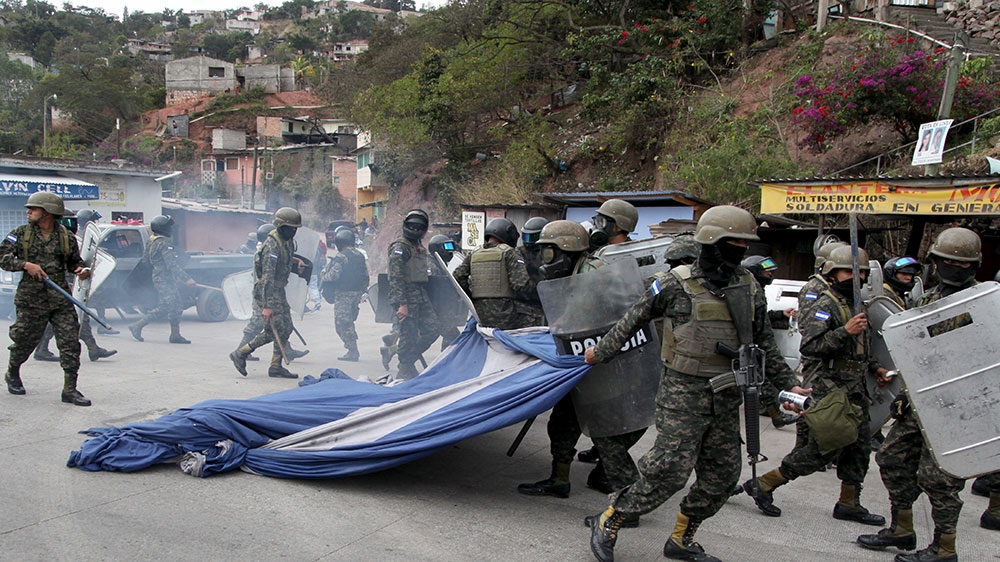 Military police drag away a giant Honduran flag they stripped away from supporters of opposition presidential candidate Salvador Nasralla during clashes in the Policarpo Paz Garcia neighbourhood of Tegucigalpa in January [File: Fernando Antonio/AP Photo] 